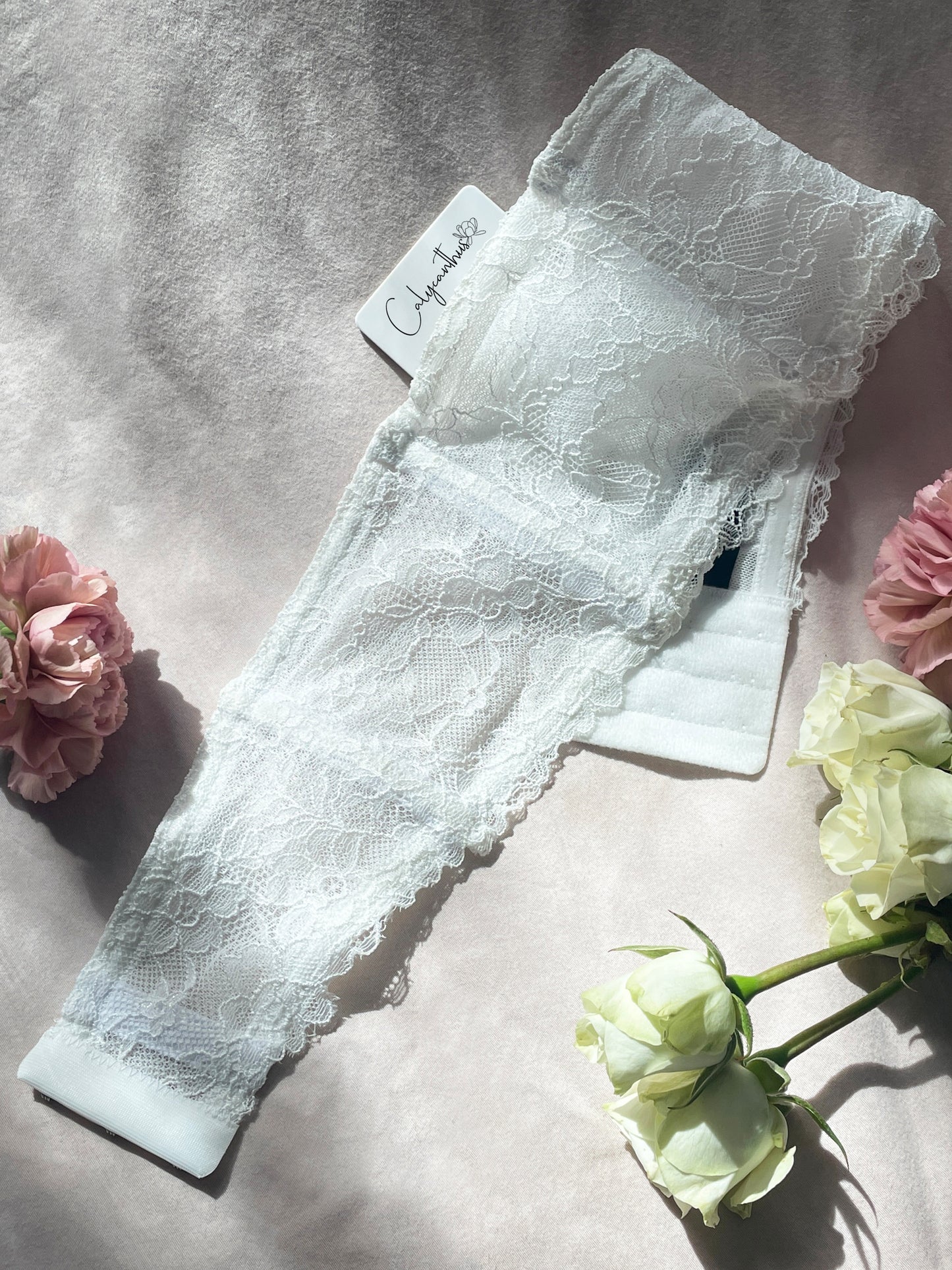 White lace garter with pocket on pink sheet with flowers