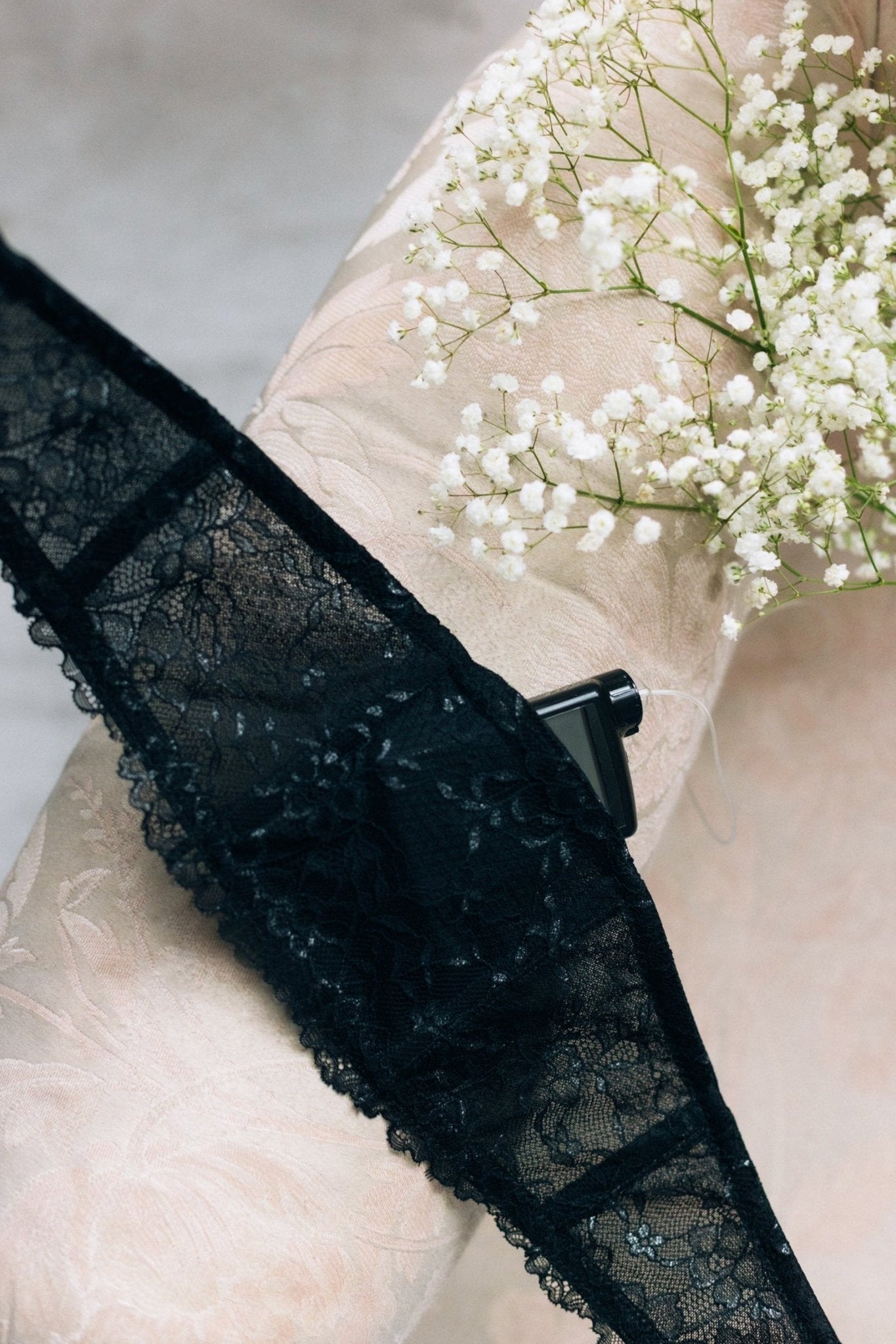 Black lace garter with pocket for insulin pump on pink couch with white flowers